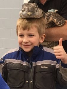 Kid with reptile on his head giving thumbs up